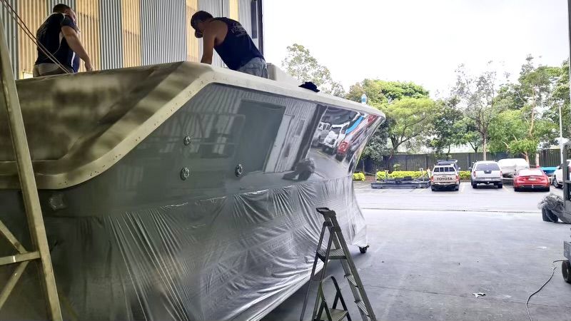 Two crew polishing the superstructure of a motor yacht